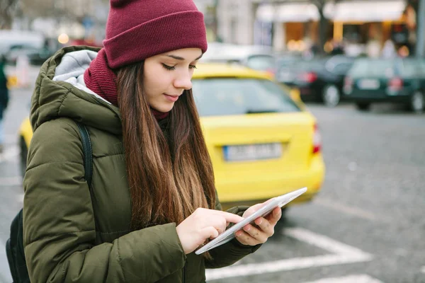 Hermosa chica turística con una tableta en una calle de Praga llama a un taxi o mira un mapa o utiliza Internet o una aplicación móvil . — Foto de Stock