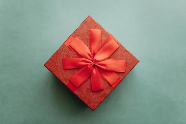 Czerwone pudełko z kokardą z prezentem na zielonym tle — Zdjęcie stockowe