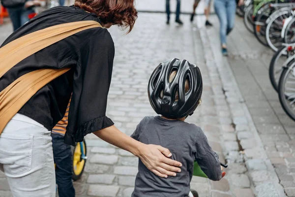 Mother teaches a child to ride a bike on a city street. — Stock Photo, Image