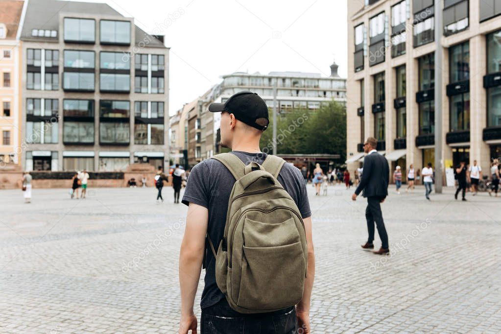 Tourist man with backpack in Leipzig admiring beautiful buildings.