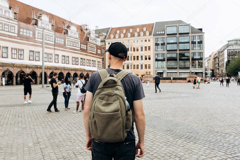 Tourist man with backpack in Leipzig admiring beautiful buildings.