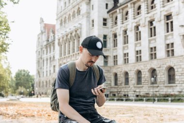 Bir turist erkek veya çocuk bir sırt çantası ile bir cep telefonu kullanır