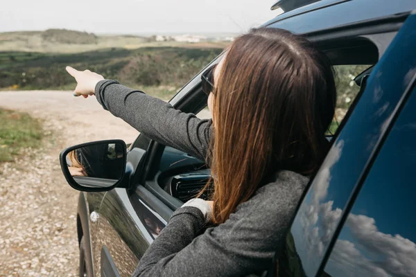 Una chica conductora o una viajera dentro del coche mira por la ventana a la carretera . — Foto de Stock