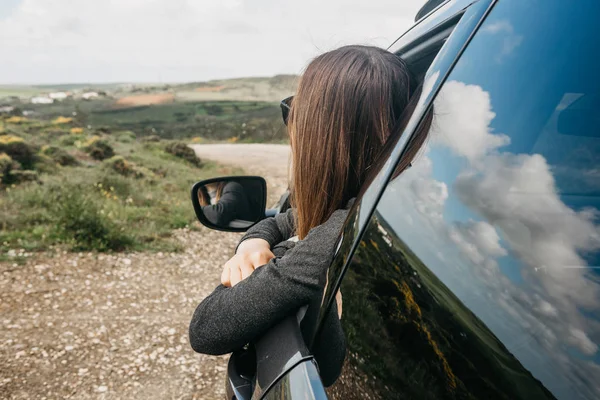 Una chica conductora o una viajera dentro del coche mira por la ventana a la carretera . — Foto de Stock
