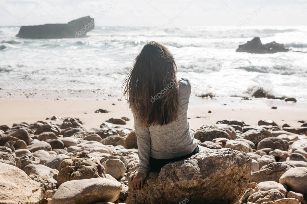 The girl in solitude admires a beautiful view of the Atlantic Ocean.