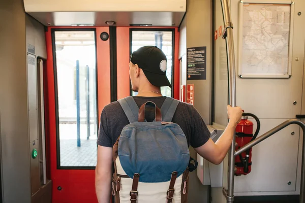 Turist adam veya öğrenci treni durdurmak bekleyen bir sırt çantası ile dışarı çıkmak.