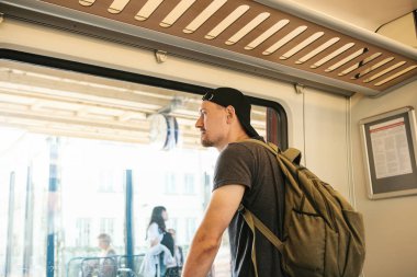 Bir sırt çantası içinde tren ile genç bir adam pencereden baktığında.
