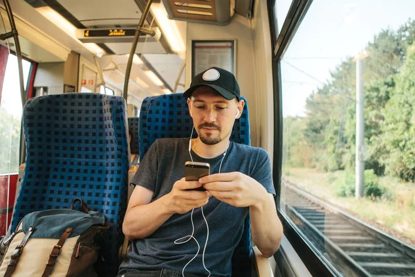 Молодой человек слушает музыку или подкаст во время путешествия в поезде — стоковое фото