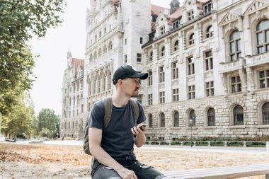 Bir turist erkek veya çocuk bir sırt çantası ile bir cep telefonu kullanır