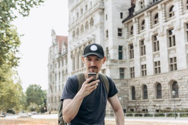 Bir turist erkek veya çocuk bir sırt çantası ile bir cep telefonu kullanır