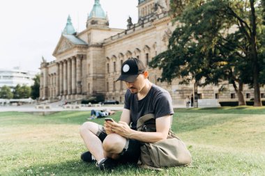 Bir turist erkek veya çocuk bir sırt çantası ile bir cep telefonu kullanır