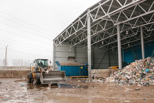 Speciale machines of bulldozer werken op de site van afval lossing in de fabriek voor afvalverwijdering. — Stockfoto