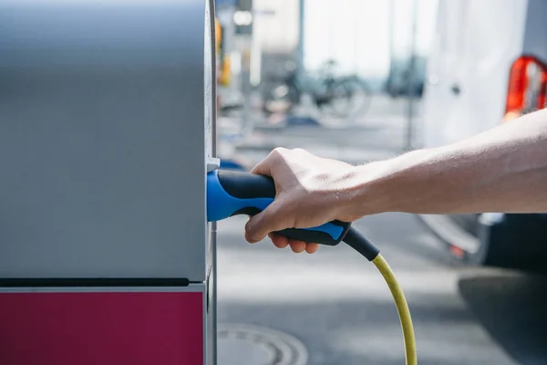 Close-up of a hand inserts a special cord or cable into a refueling station for refueling an electric car. — Stock Photo, Image