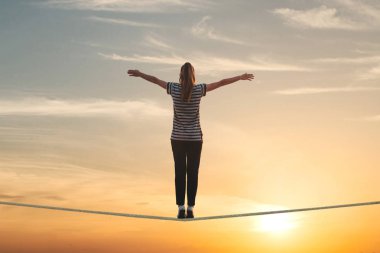 Bir kız ipe standları ve gün batımını karşı ellerini tutarsa.