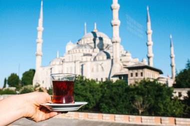 Sultanahmet Camii manzaralı terasında geleneksel Türk çay tutan kadın.