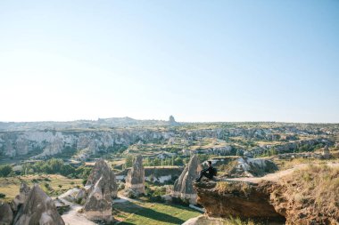 Bir adam bir sırt çantası ile Kapadokya Türkiye'de bir tepe üstünde oturuyor.