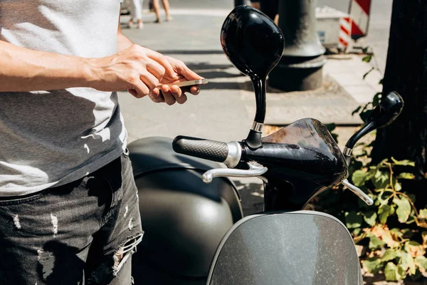 Un gars ou un touriste active ou loue un scooter électrique à l'aide d'une application mobile sur un téléphone portable . — Photo