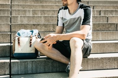 Bir turist veya öğrenci merdivenlerde oturur, aittir ve bir cep telefonu kullanır