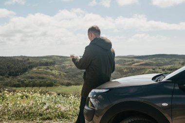 Bir turist adamın arabanın yanında daha fazla seyahat için bölgenin haritasına bakar