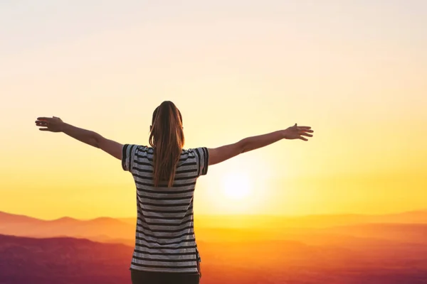 A menina admira uma bela vista do nascer do sol ou do pôr do sol e levanta as mãos — Fotografia de Stock