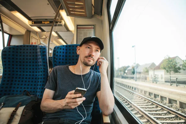 A young man listens to a music or podcast while traveling in a train