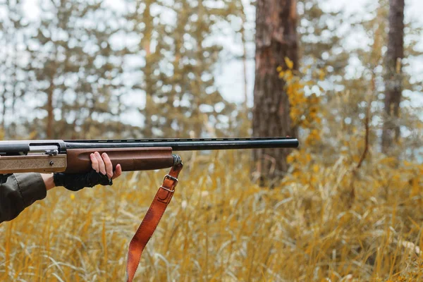 Woman hunter holding a gun in the woods