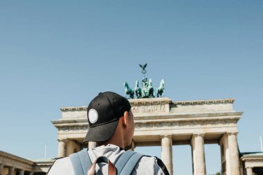 Bir turist veya Almanya'da Berlin Brandenburg Gate yakınındaki bir sırt çantası ile bir öğrenci.