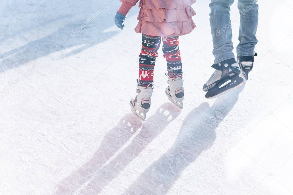 Father and daughter skate on the rink during the winter holidays.