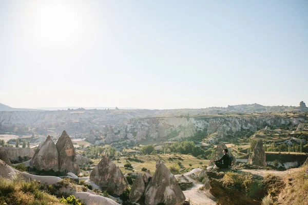 A man with a backpack sits on top of a hill in Cappadocia in Turkey. — Stock Photo, Image
