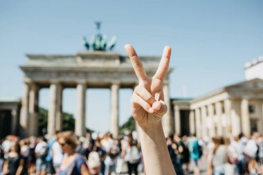 Kızı arka planda Berlin Brandenburg Kapısı'nın barış işareti gösterir.
