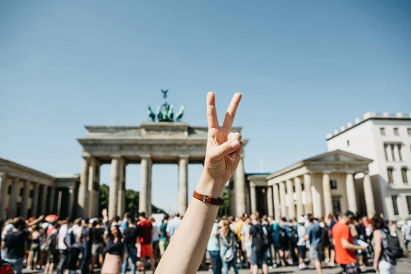 Девушка Показывает Знак Мира Фоне Бранденбургских Ворот Размывает Неузнаваемых Людей — стоковое фото