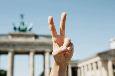 Kızı arka planda Berlin Brandenburg Kapısı'nın barış işareti gösterir
