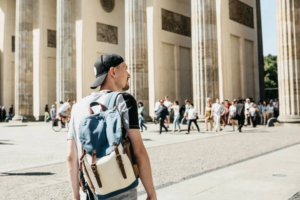 Un turista o un estudiante con una mochila cerca de la Puerta de Brandenburgo en Berlín en Alemania, mira los lugares de interés . — Foto de Stock