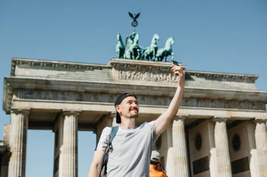 Tourist guy taking a selfie or taking pictures of sights clipart