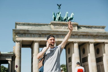 Bir turist ya da bir adam bir sırt çantası ile bir cep telefonu üzerinde konuşurken ve birisi eliyle tebrik.