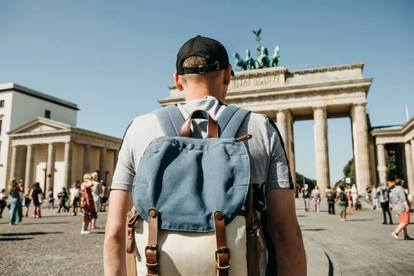 Un turista o un estudiante con una mochila cerca de la Puerta de Brandenburgo en Berlín en Alemania, mira los lugares de interés . — Foto de Stock