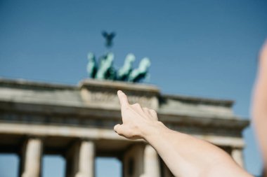 Turist veya adam elini Berlin Brandenburg Kapısı üzerinde gösterir