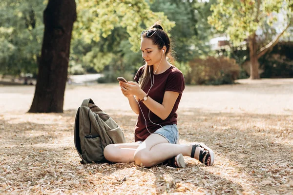 Joven hermosa chica positiva está sentado y escuchando música — Foto de Stock