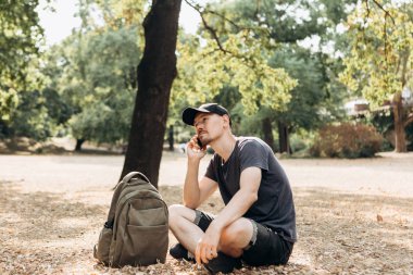 Bir adam bir cep telefonu üzerinde konuşurken bir sırt çantası ile.