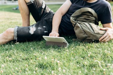 Genç bir adam çim üzerinde yalan ve internette sörf veya çevrimiçi ya da başka bir şey.