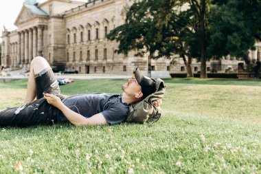Bir öğrenci çimenlerin üzerinde yatıyor ve müzik dinliyor.