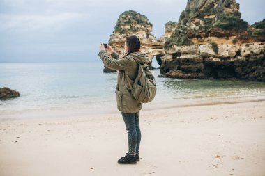 Kız turist Atlantik kıyısında bekleyen bir güzel manzara fotoğrafçılığı bir sırt çantası ile