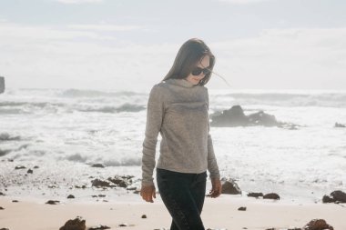 Güzel bir genç kız sahil boyunca yürür.