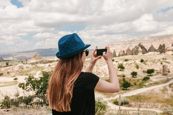 Un turista hace una foto en el teléfono en memoria de una hermosa vista de las colinas de Capadocia en Turquía. Viajes, turismo, vacaciones . — Foto de Stock