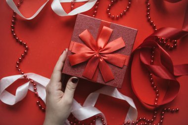 Kız bir hediye ile kırmızı bir kutu tutuyor.