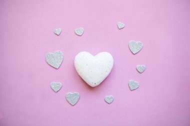 Beyaz kalp pembe bir arka plan üzerinde ve yakınlarında çok küçük kalp.