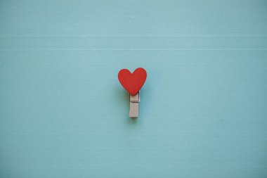 En az bir tarzda mavi bir arka plan üzerinde bir kalp ile clothespin