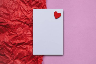 Beyaz boş sayfaya kırmızı bir arka plan üzerinde kırmızı bir kalp