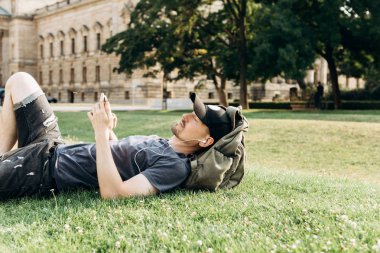 Bir öğrenci çimenlerin üzerinde yatıyor ve müzik dinliyor.