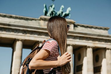 Bir turist veya Almanya'da Berlin Brandenburg Gate yakınındaki bir sırt çantası ile bir öğrenci.